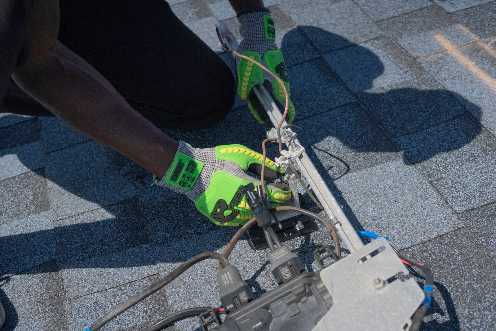 Mains gantées fixant un équipement sur une toiture en chantier